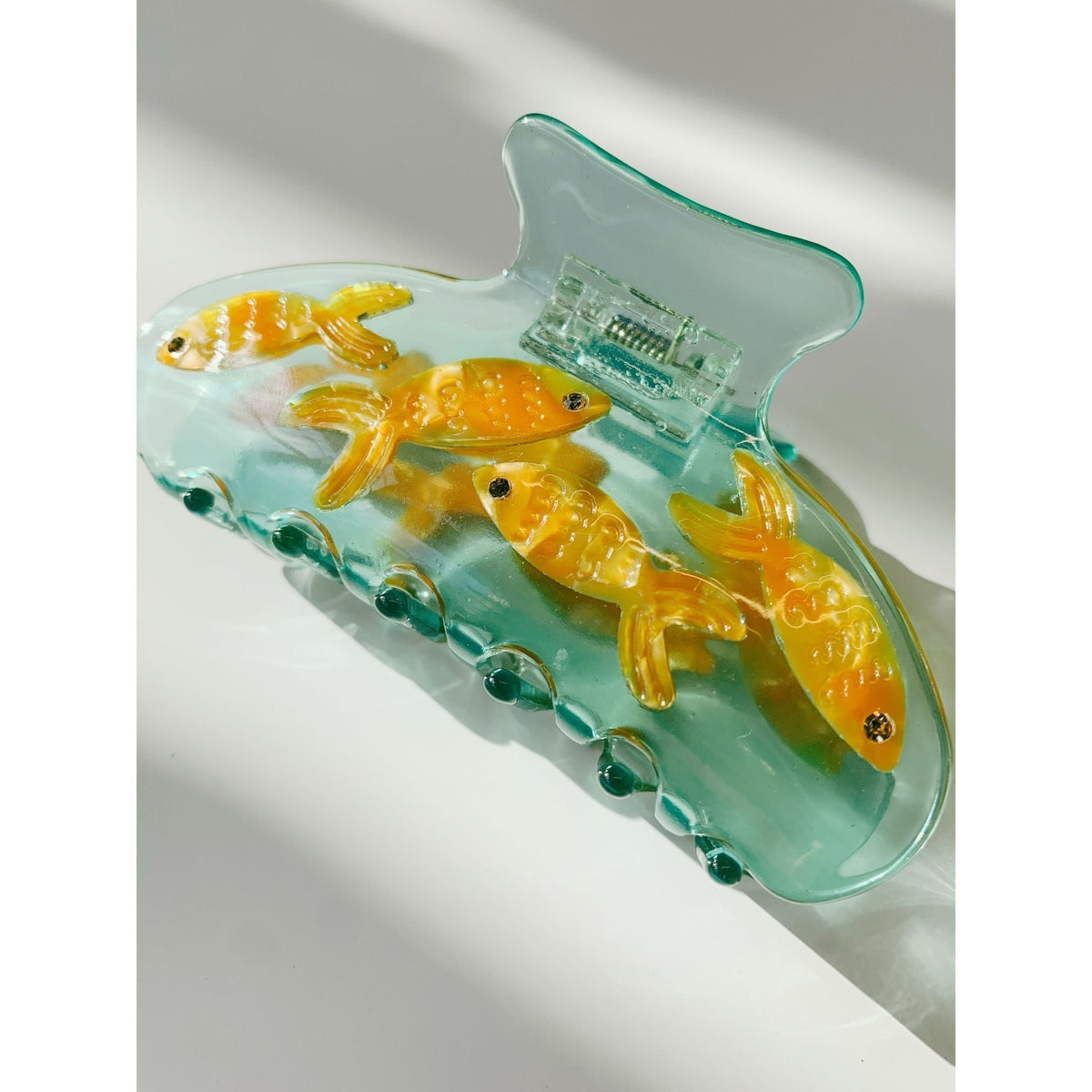 Goldfish hair claw clip, close angled view with teal shell and four orange fish