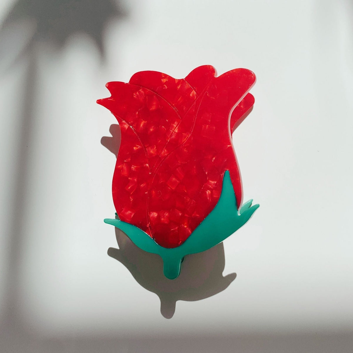 Red rosebud hair claw clip with green leaves, front view