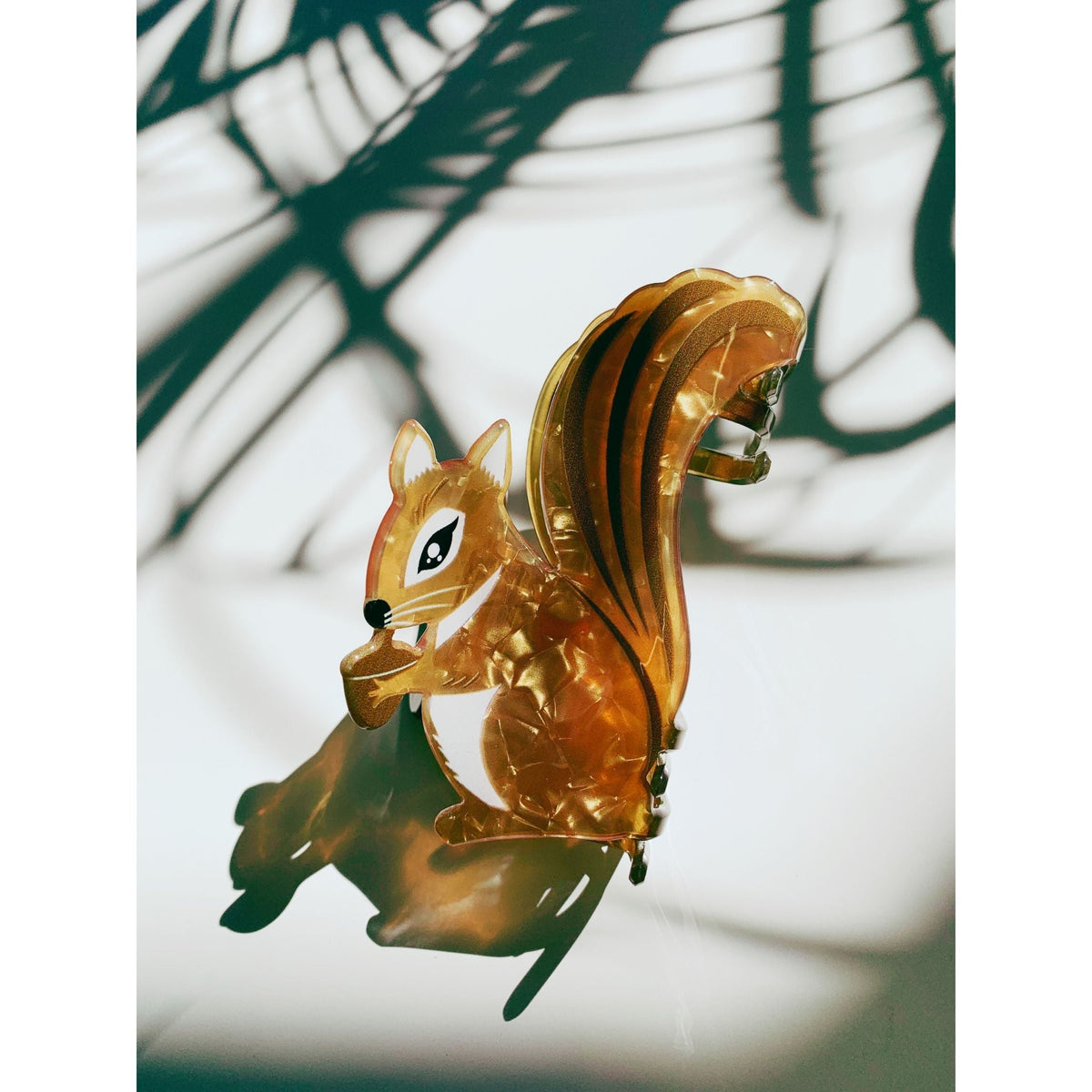 Amber squirrel hair claw holding an acorn, shown from front
