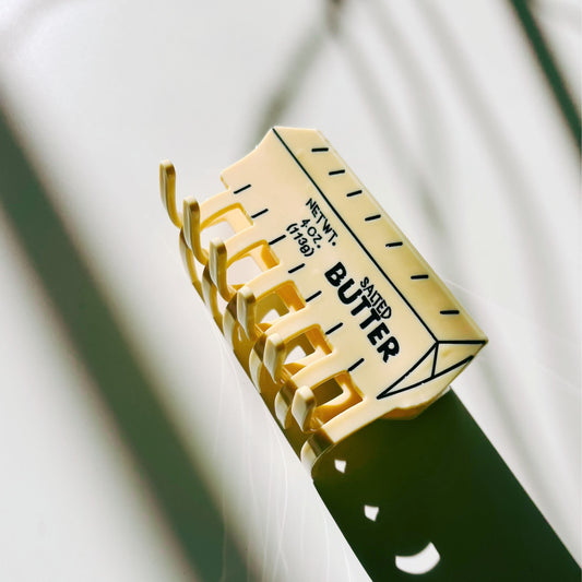 Yellow butter-shaped hair claw clip with serrated prongs and top label