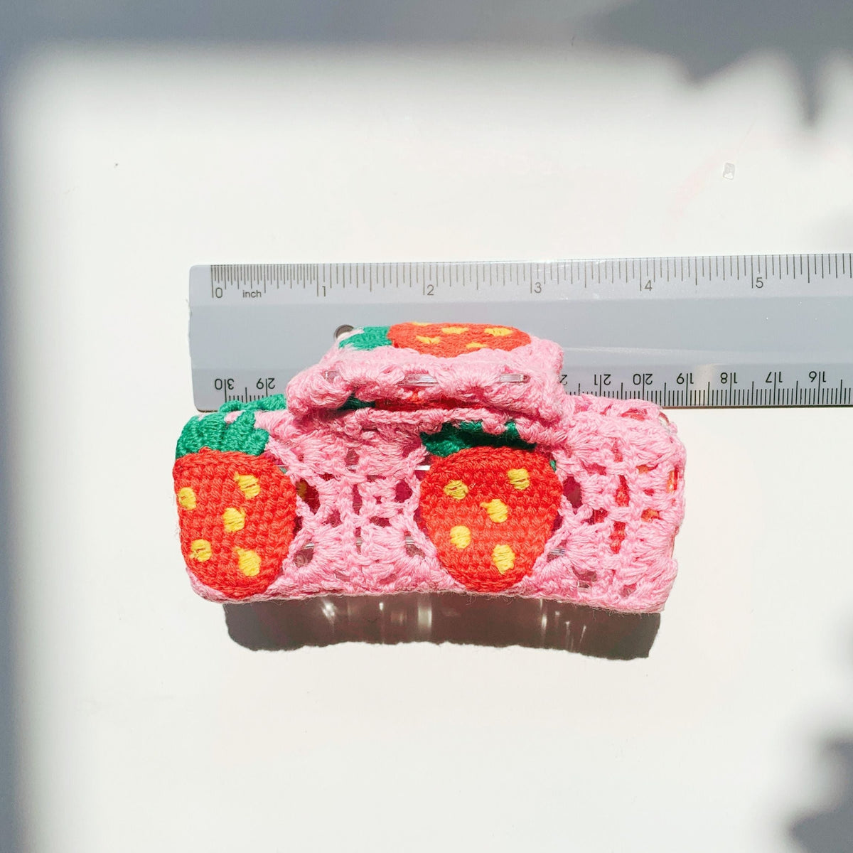 Pink crocheted hair claw with strawberry granny squares and green leaf details