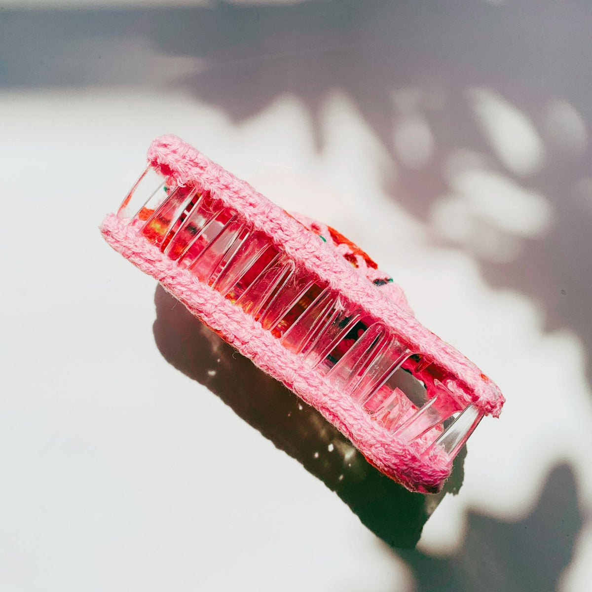 Pink crocheted hair claw with clear plastic teeth at the top