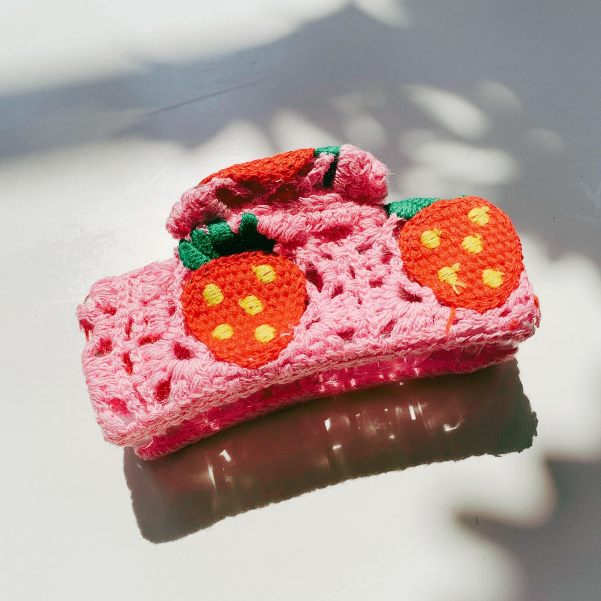 Pink crochet hair claw with orange strawberry appliques and green leaf trim