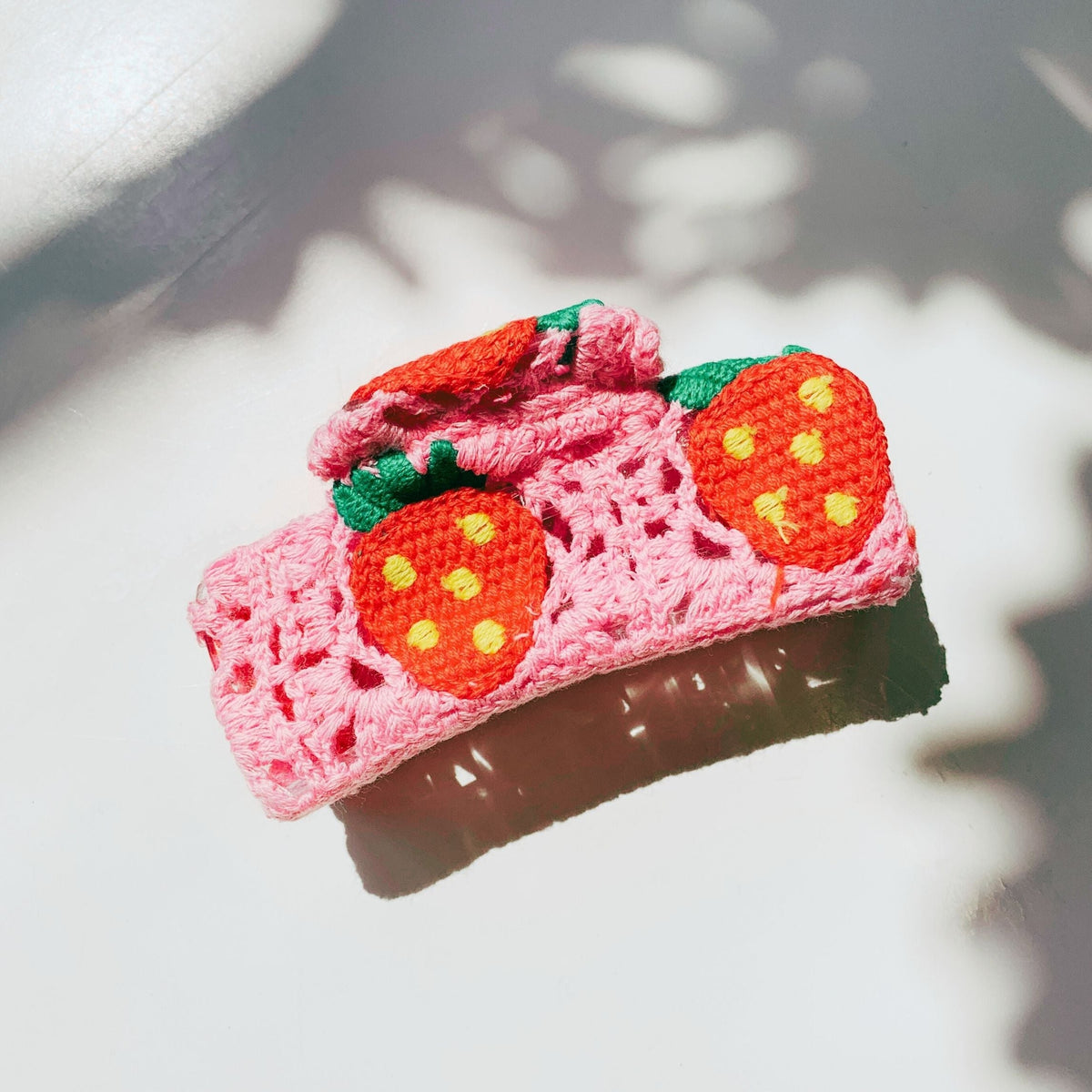 Pink crochet hair claw with orange strawberry appliques and green leaf accents