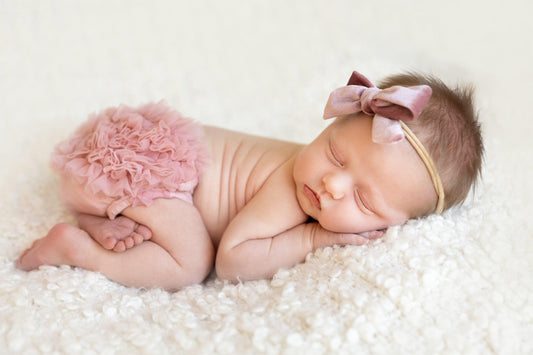 Pink ruffle bum bloomer on a baby with layered frills and bow details