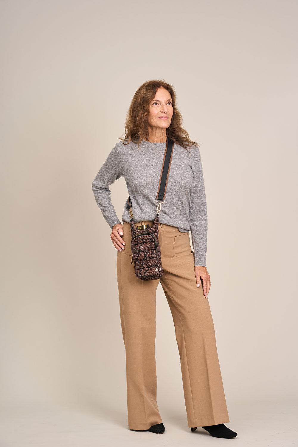 Snake-print HydroBag crossbody on model wearing gray top and tan pants