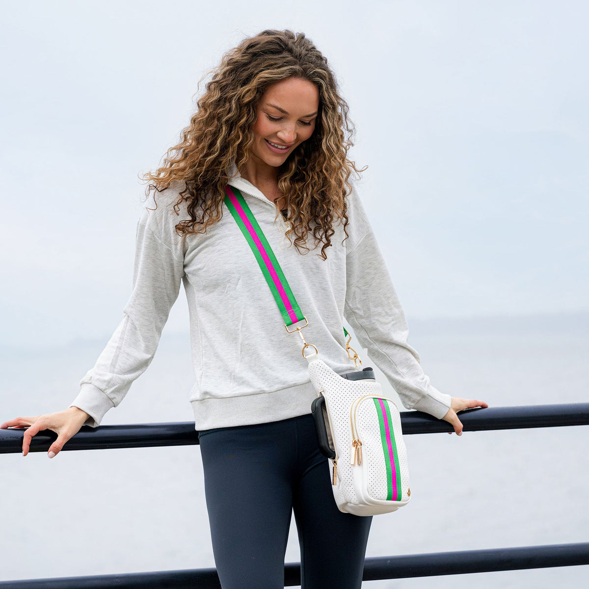 White striped crossbody HydroBag on a woman, attached to a green-and-pink shoulder strap