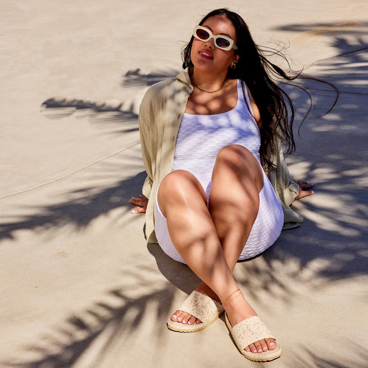 Speckled slide sandals on feet, open toe crossover straps and tan rubber sole.