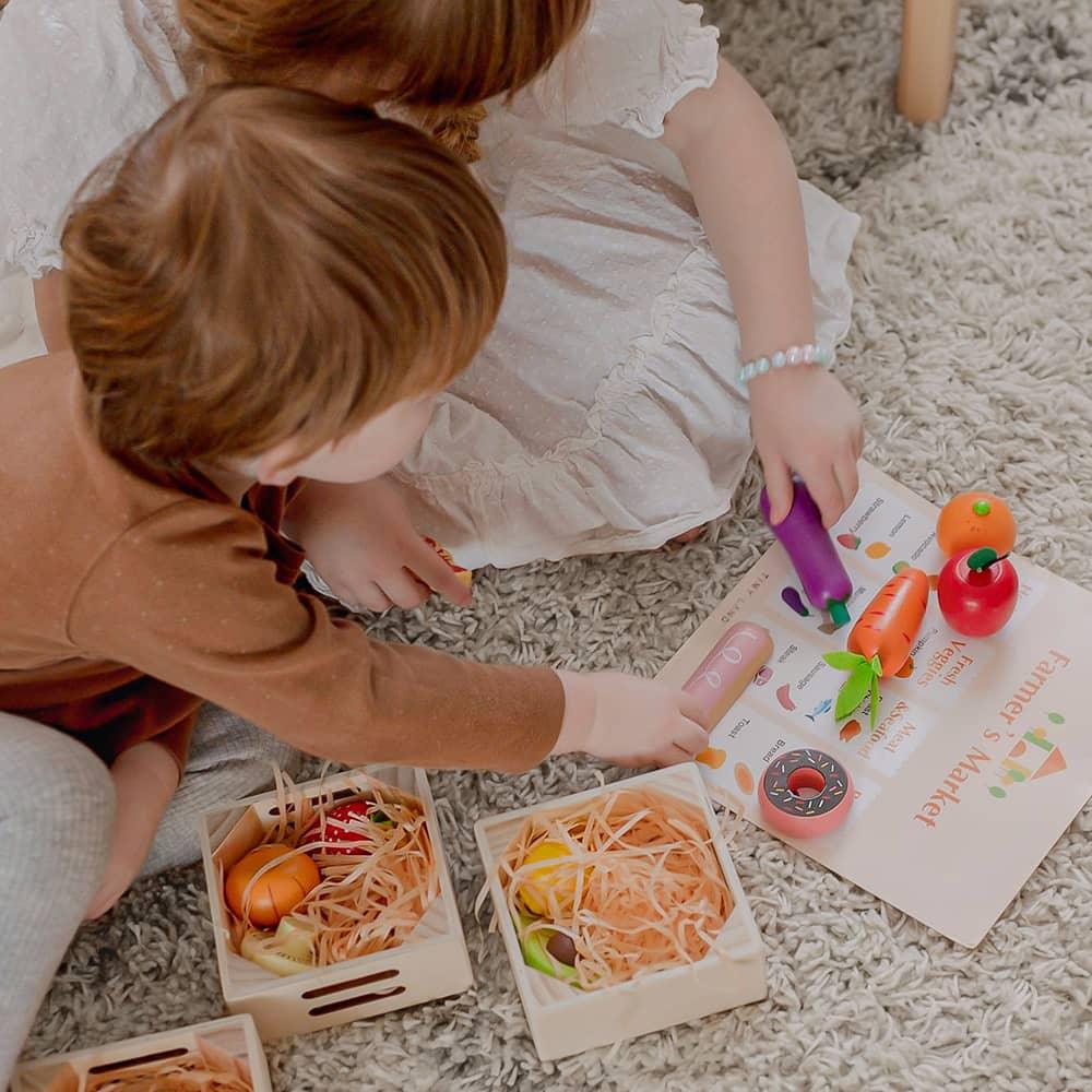 Wooden play food, crates and market guide arranged for pretend shopping