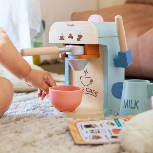 Kids play coffee maker with pastel cups and milk container on tabletop