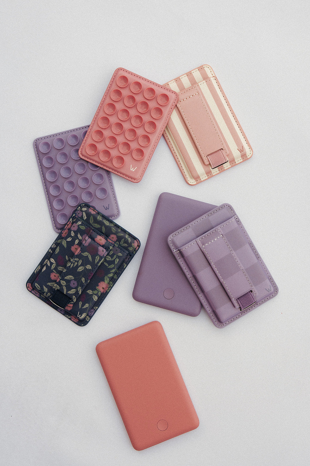 Assorted magnetic phone wallets in purple, pink, and orange with card slots and straps.