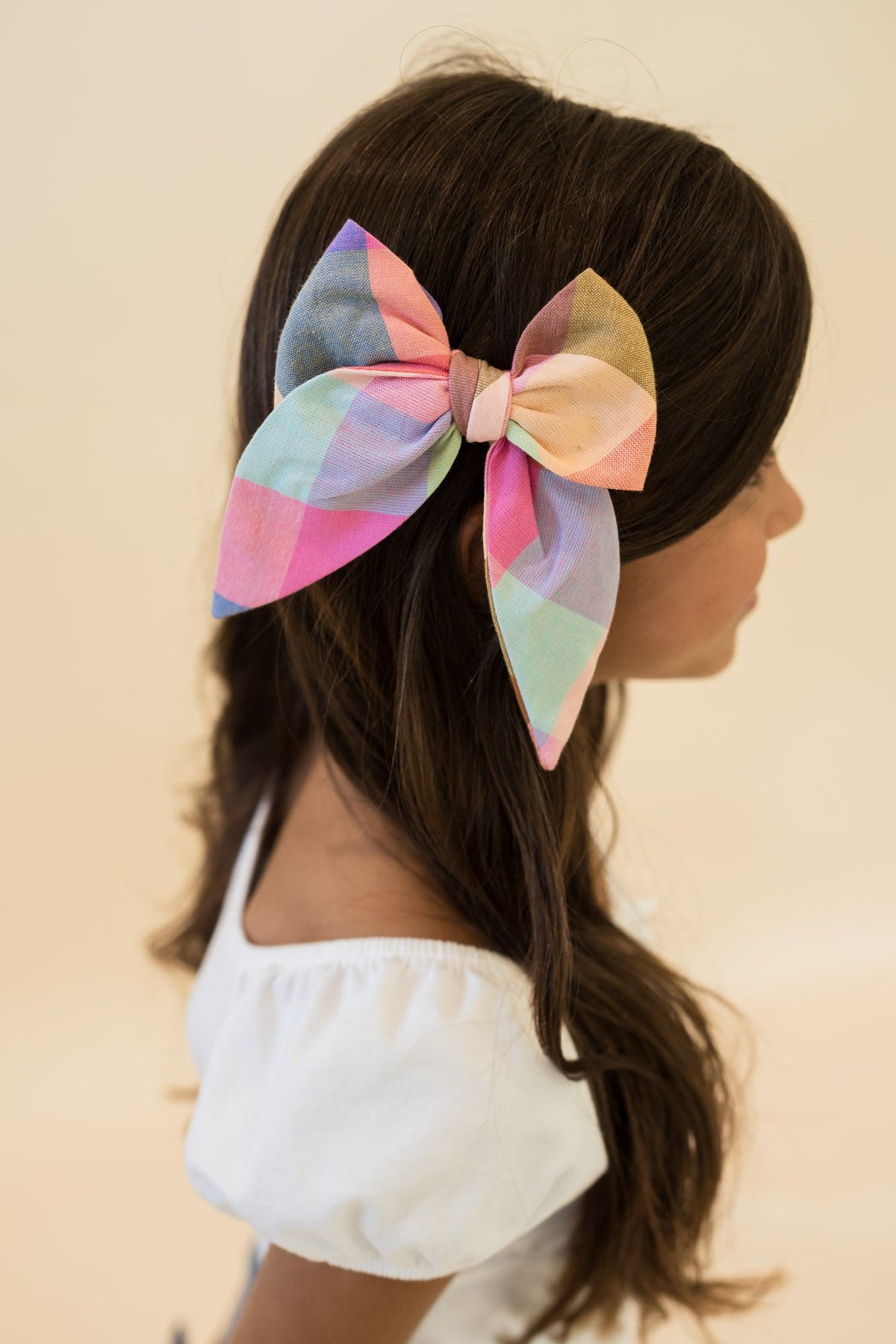 Plaid hair bow on dark hair, tied ribbon with pastel and navy blocks