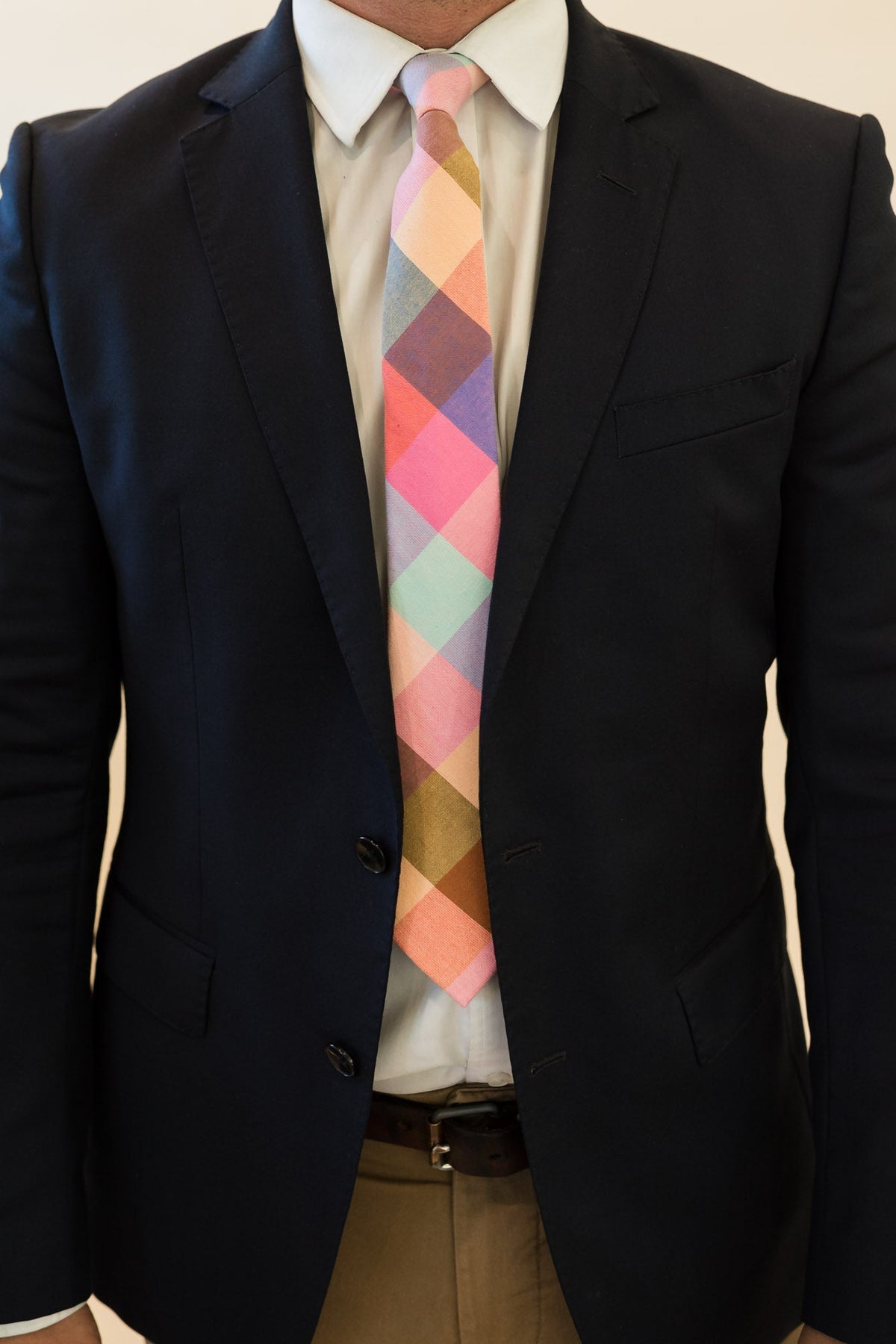Men's plaid tie worn with dark suit jacket and white shirt; multicolor diamond pattern