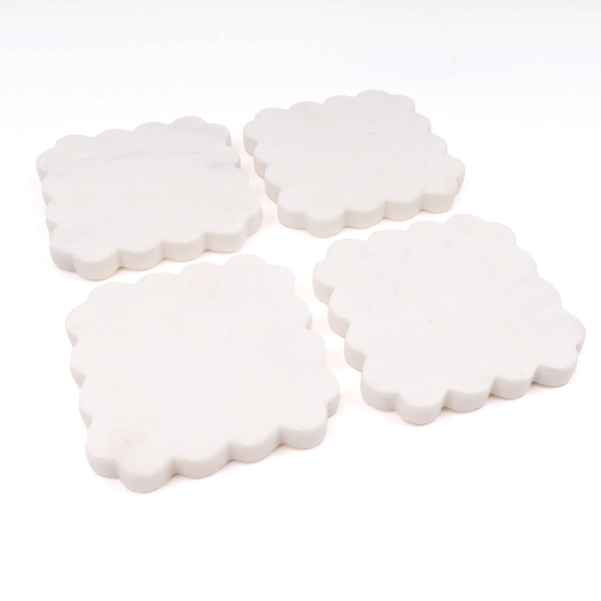 Set of four scalloped white coasters with rounded edges