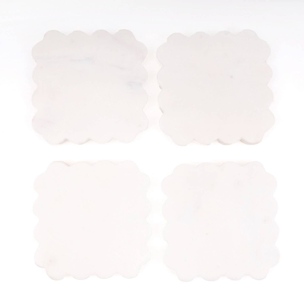 Four scalloped white coasters with rounded scallop edges