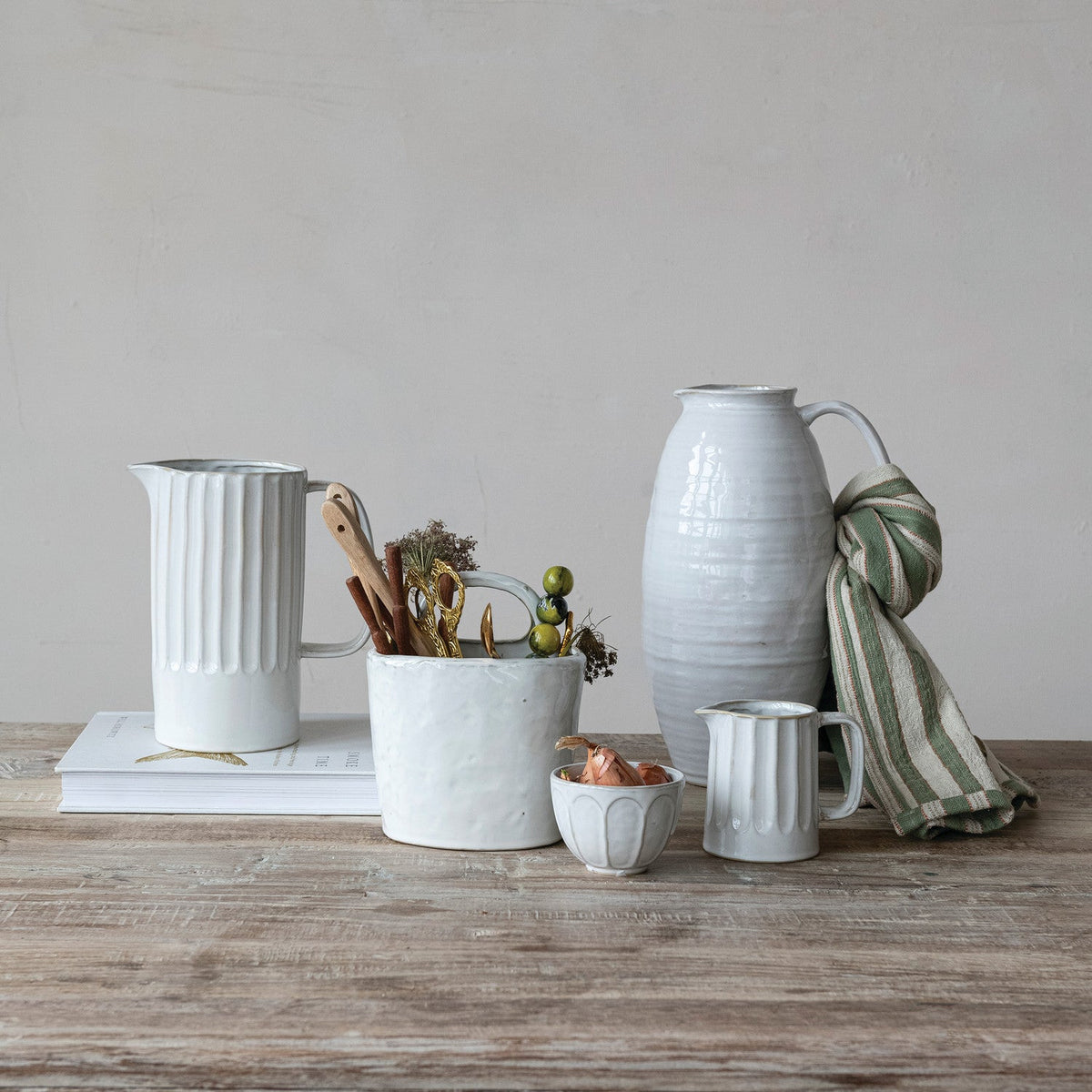 White stoneware pitcher with ribbed body, pour spout, and curved side handle