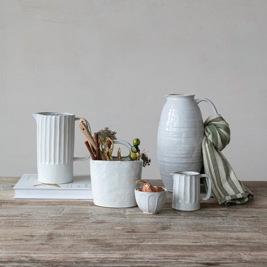 White stoneware pitcher with ribbed body, pour spout, and curved side handle