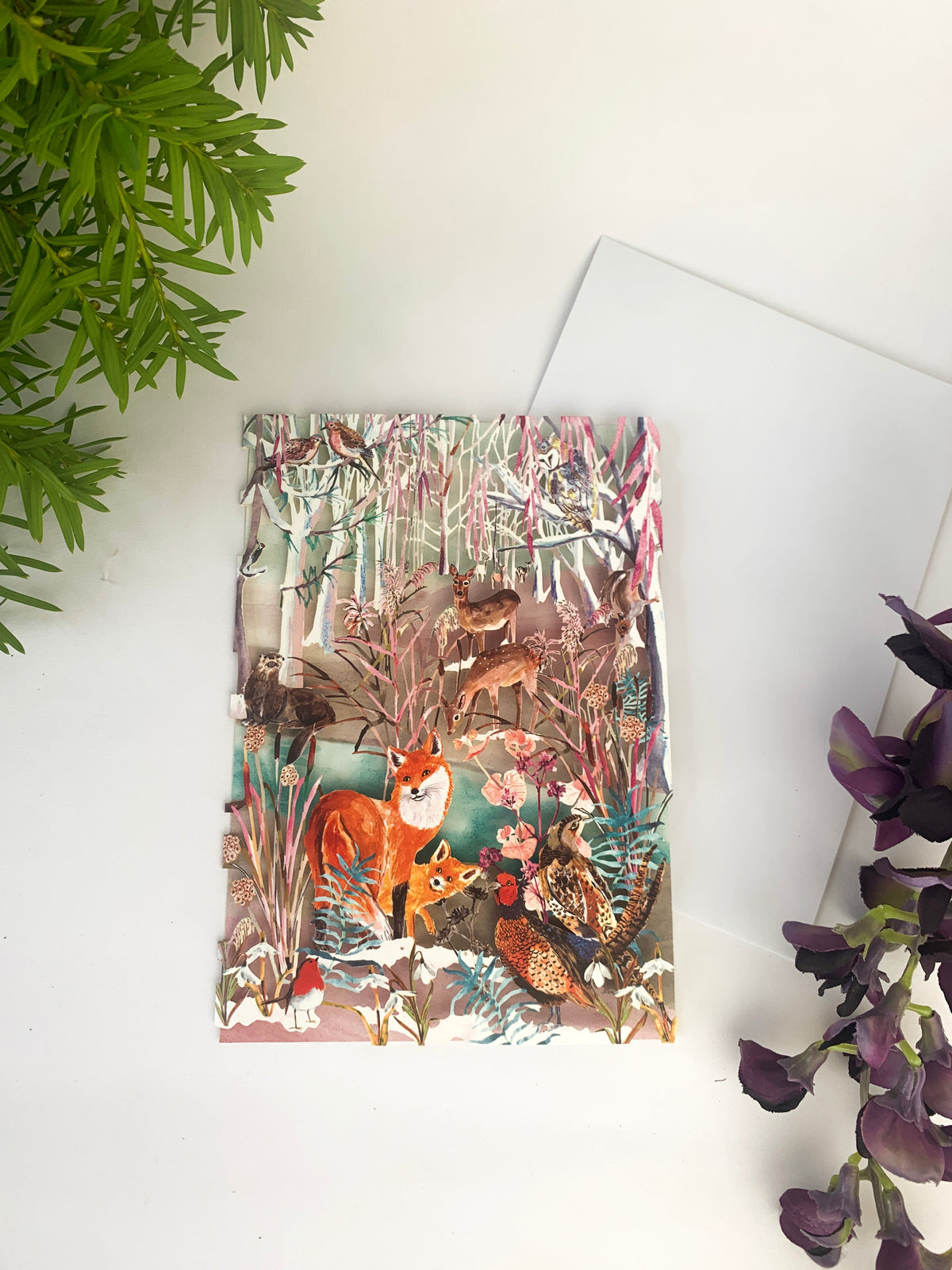 Laser-cut Christmas card featuring foxes and forest animals in snowy woodland, folded