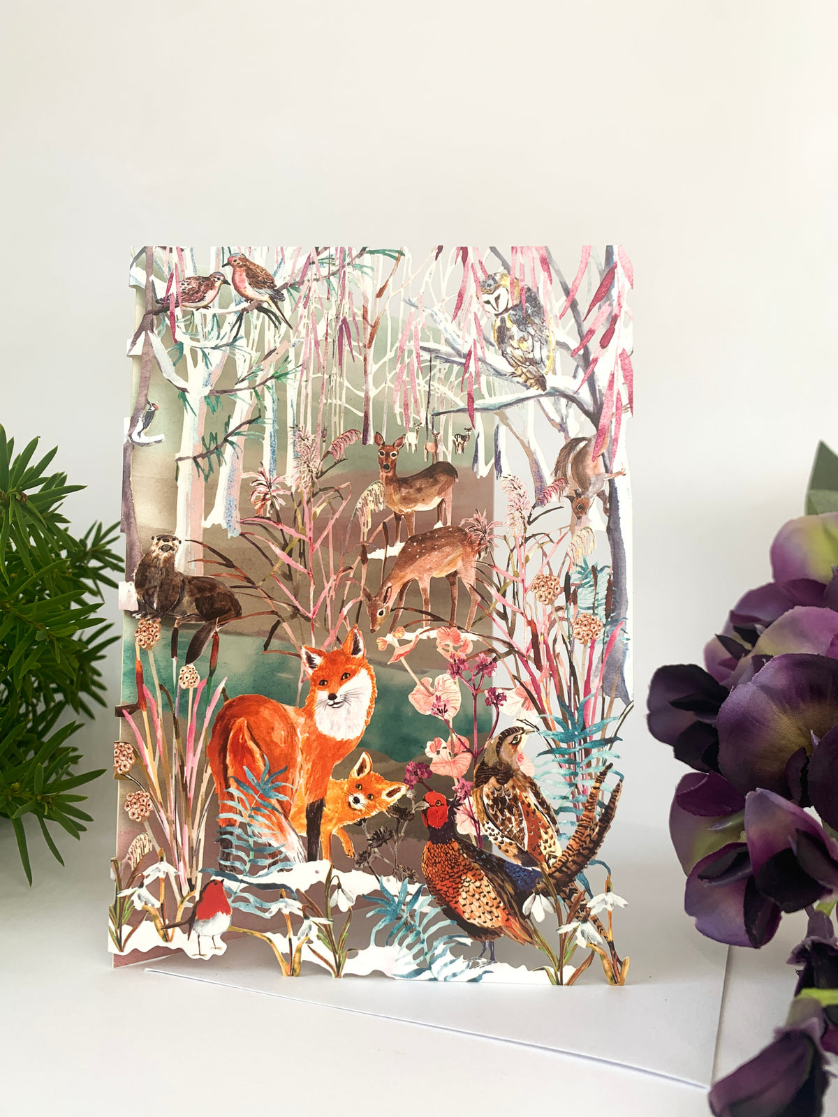 Laser-cut Christmas card with foxes and woodland animals in winter trees scene