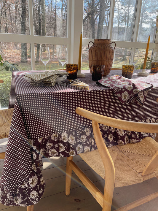 Wine gingham tablecloth with a floral ruffled border draped over a dining table