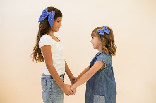 Petite hair bow in blue on a child’s hair, geometric pink and orange print