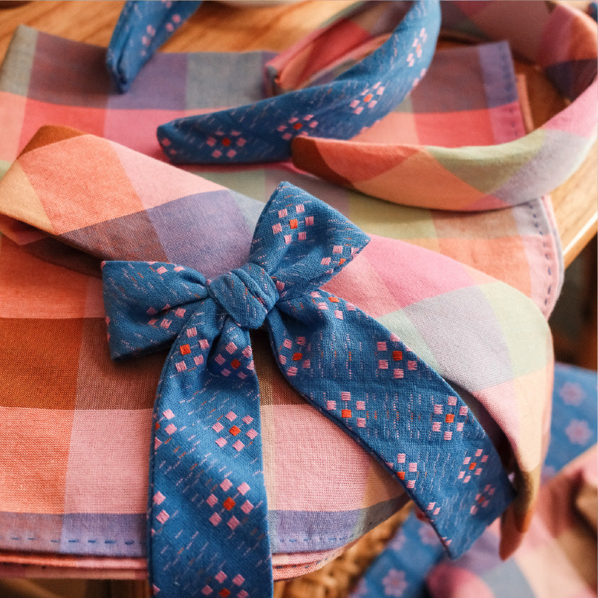 Plaid pre-tied bow tie on striped shirt collar with blue check pattern knot