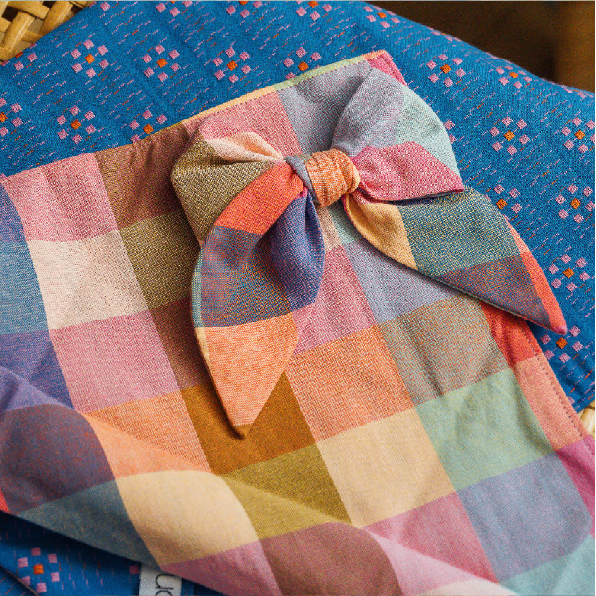 Petite plaid hair bow on patterned fabric; pink, blue, teal, and orange checks