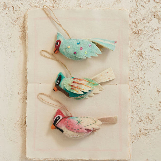 Wool felt bird ornaments on cloth, teal and blue wings plus red bird with string