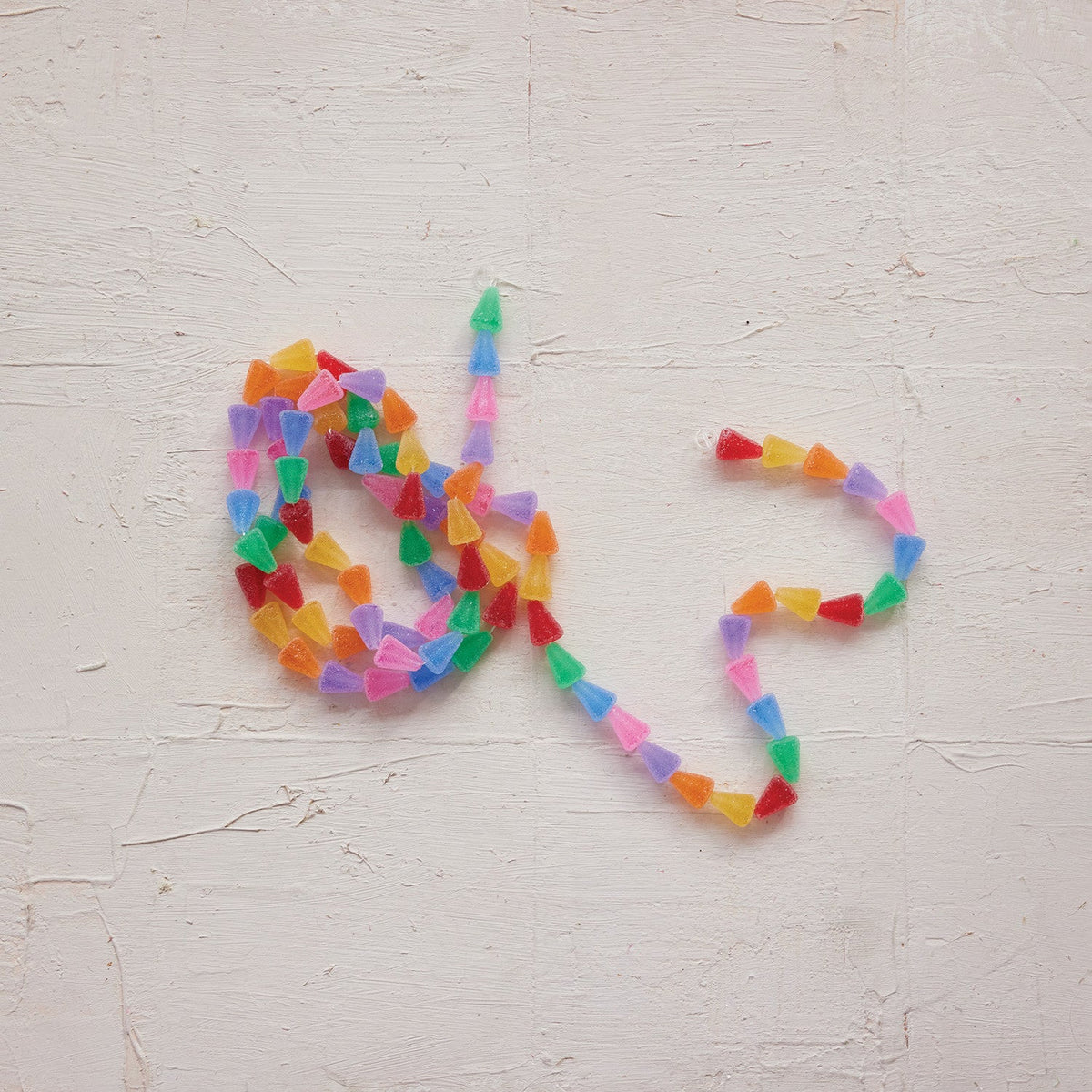Multicolor candy garland arranged in a heart shape on a light wall