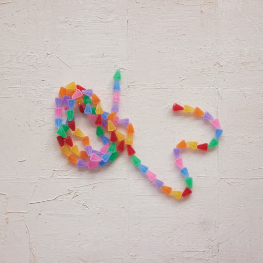 Multicolor candy garland arranged in a heart shape on a light wall