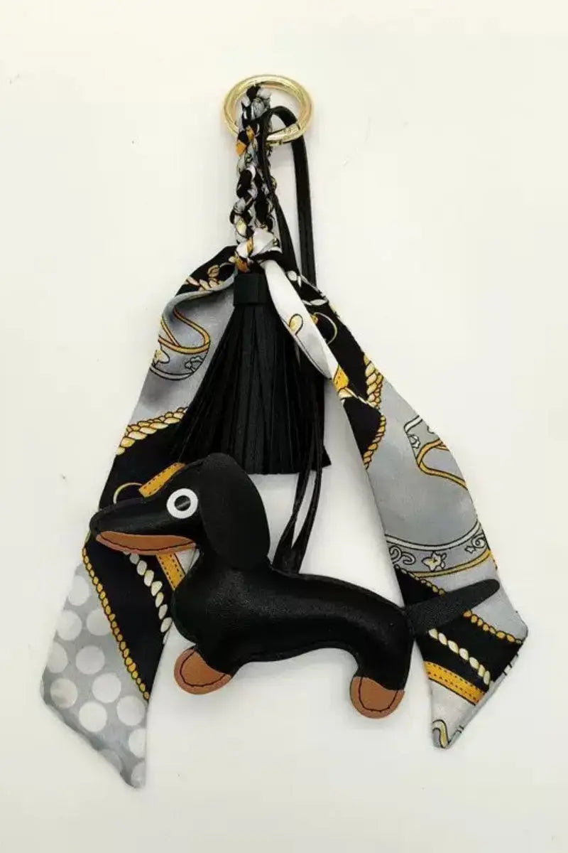 Fringed dachshund leather bag charm with black tassel and patterned scarf ring, gold clasp