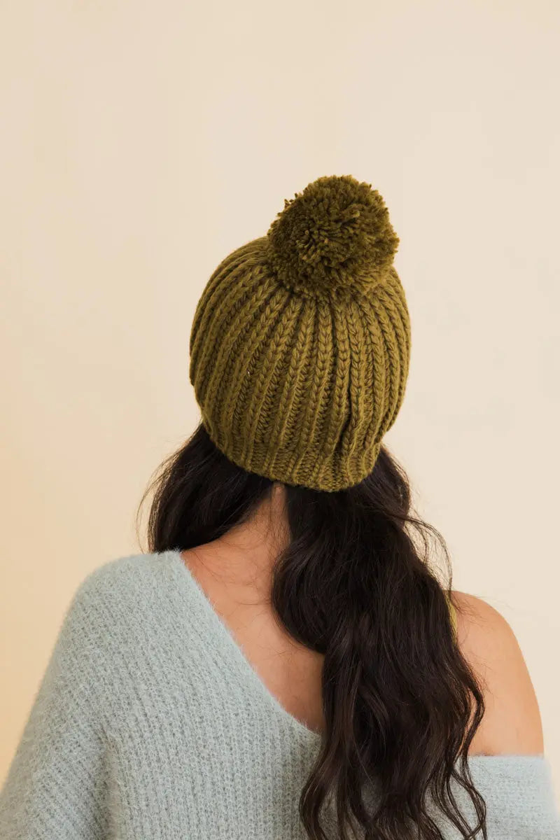 Army green cable knit pom beanie viewed from the back, ribbed brim