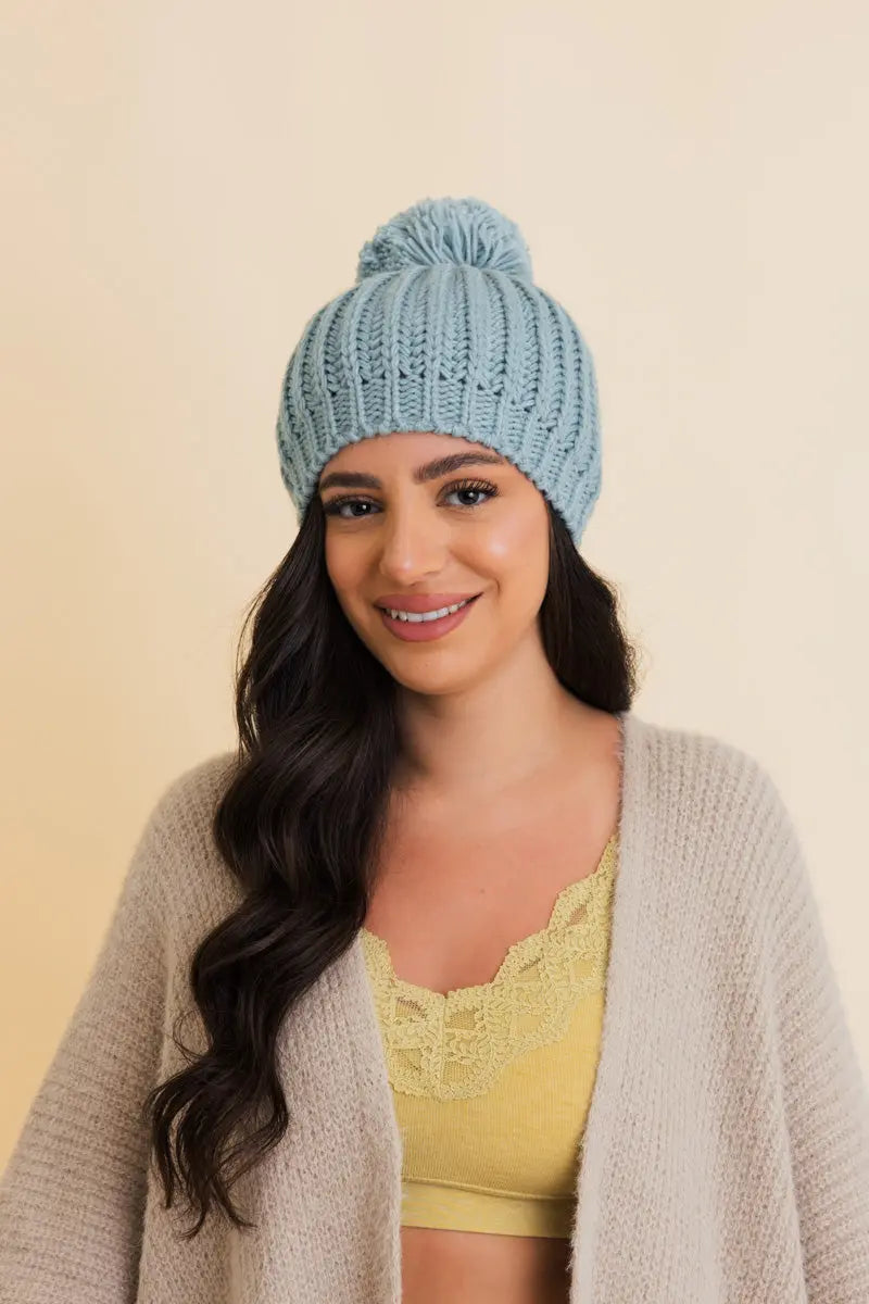 Sea blue chunky cable-knit pom beanie with folded cuff and knit pom top.