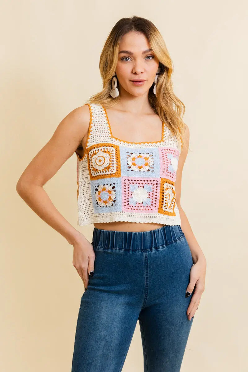 Crochet crop top with square patchwork blocks and floral motifs, mustard, pink, and white
