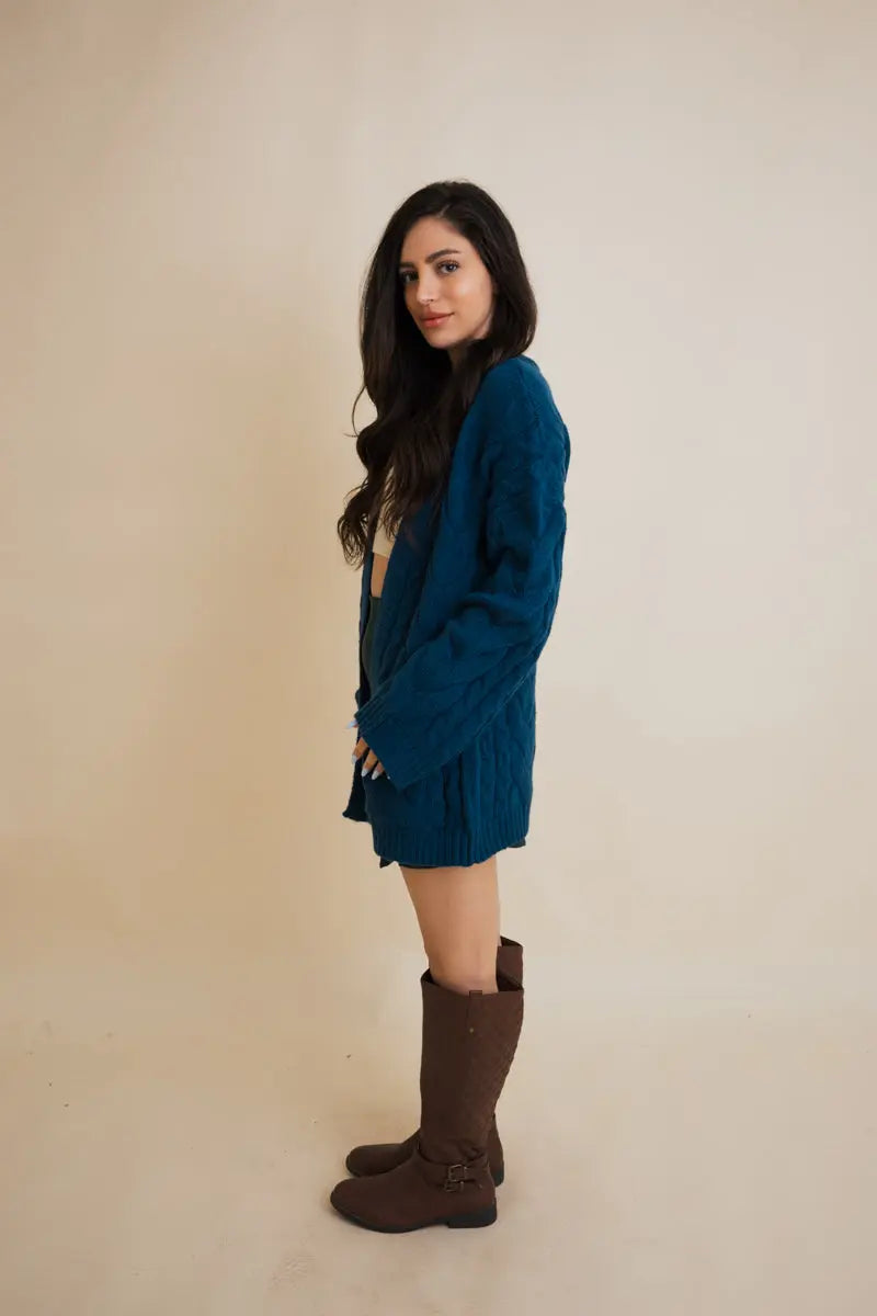 Teal cable-knit open cardigan with long sleeves and cable texture, side view