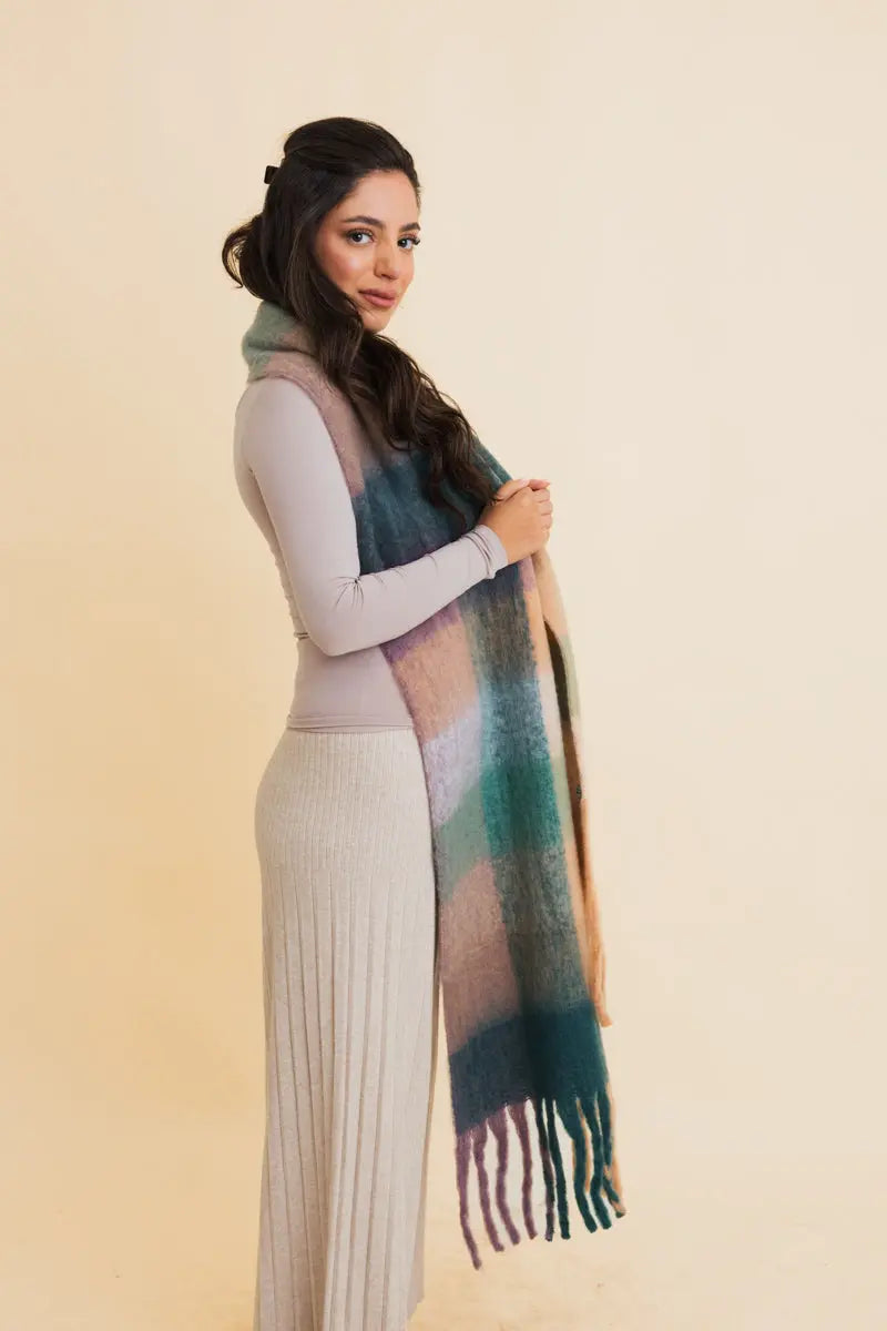 Oversized plaid fringe scarf draped over shoulder in teal and dark blue blocks