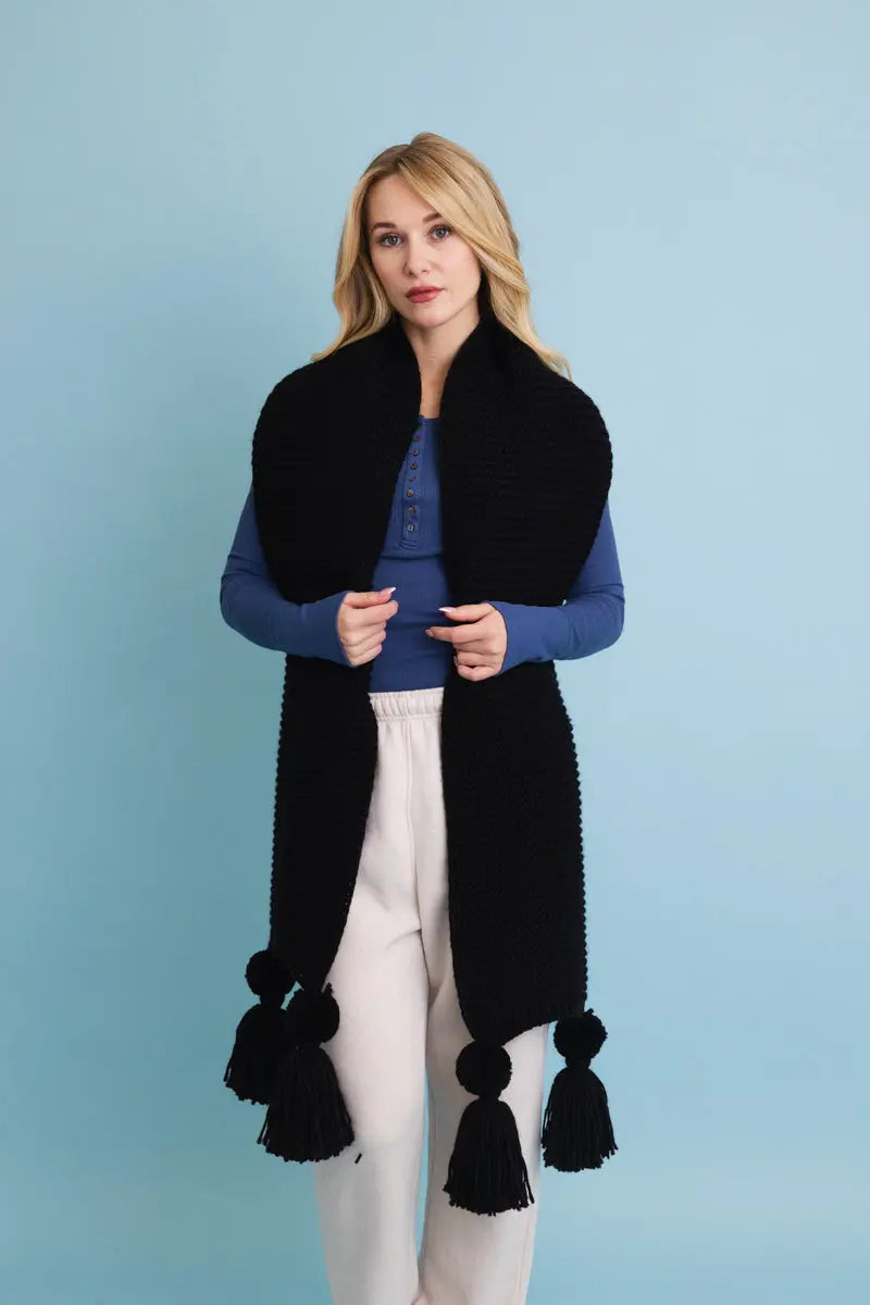 Black knit scarf with long tassel pom-poms and an open draped shape