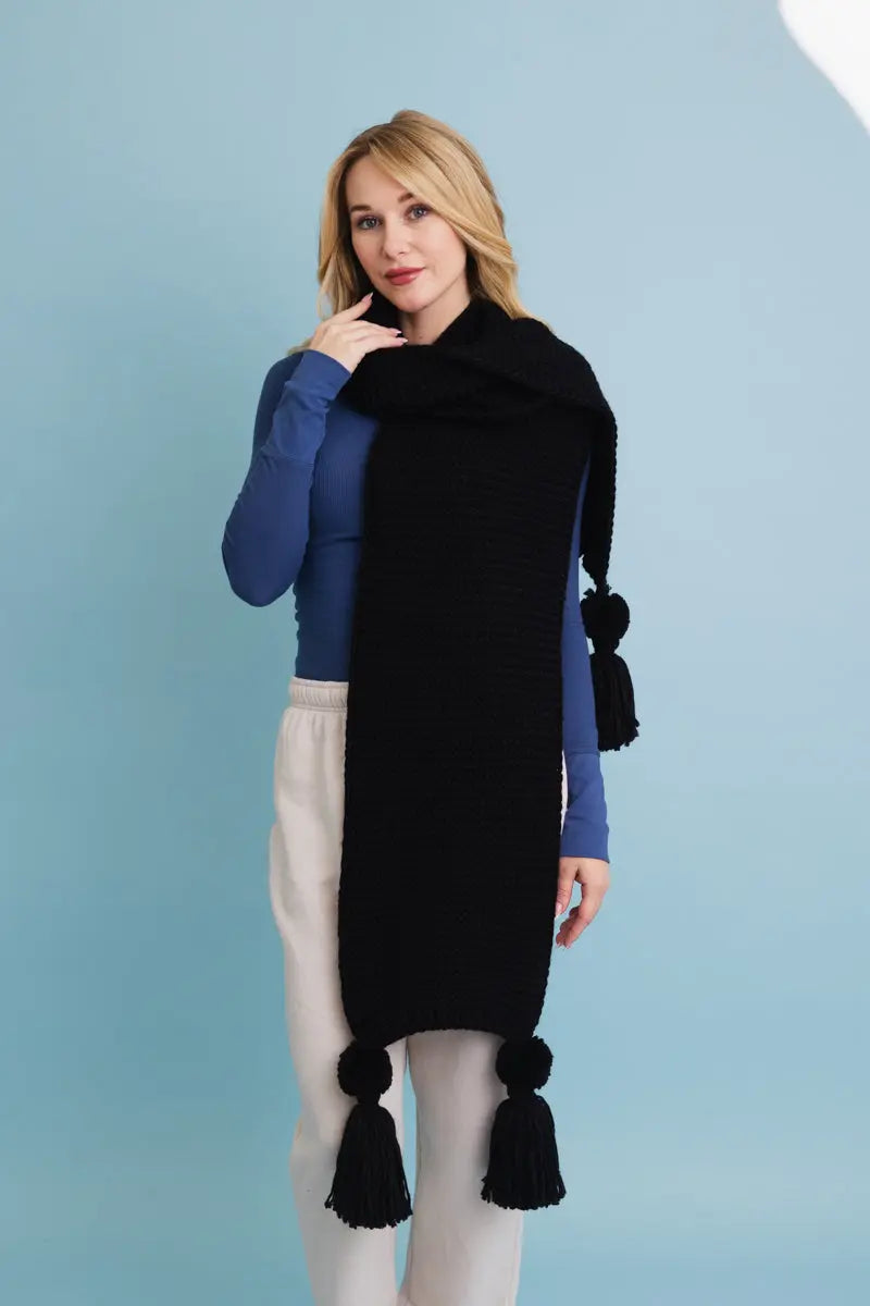 Black knit scarf with long tassel pom-poms and a soft draped wrap