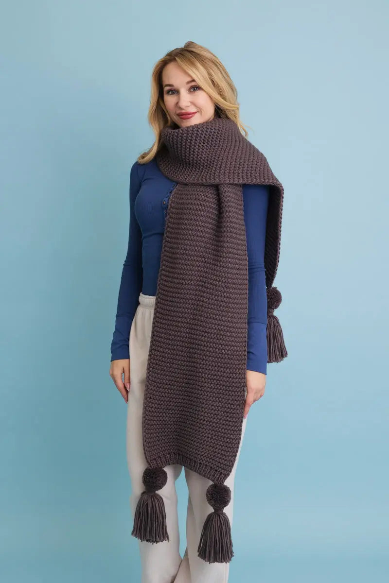 Gray knit scarf with chunky texture and pom-pom tassels at both ends