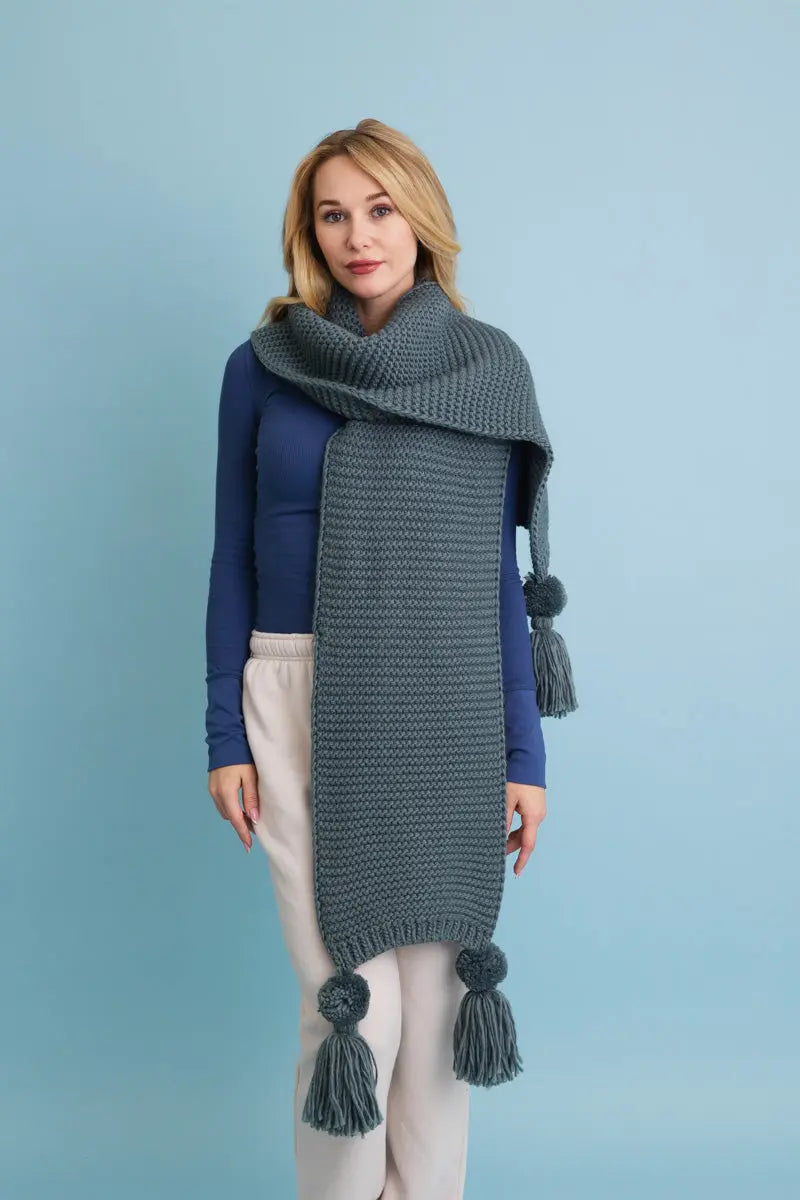 Slate gray knit scarf with tassel pom-poms and a wide cozy drape