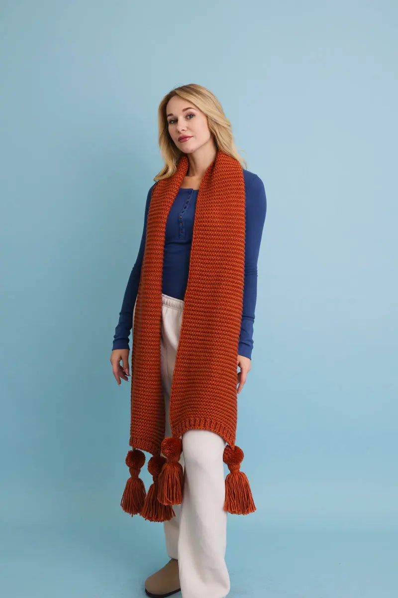 Rust orange chunky knit scarf with tassel pom-poms and long draped ends