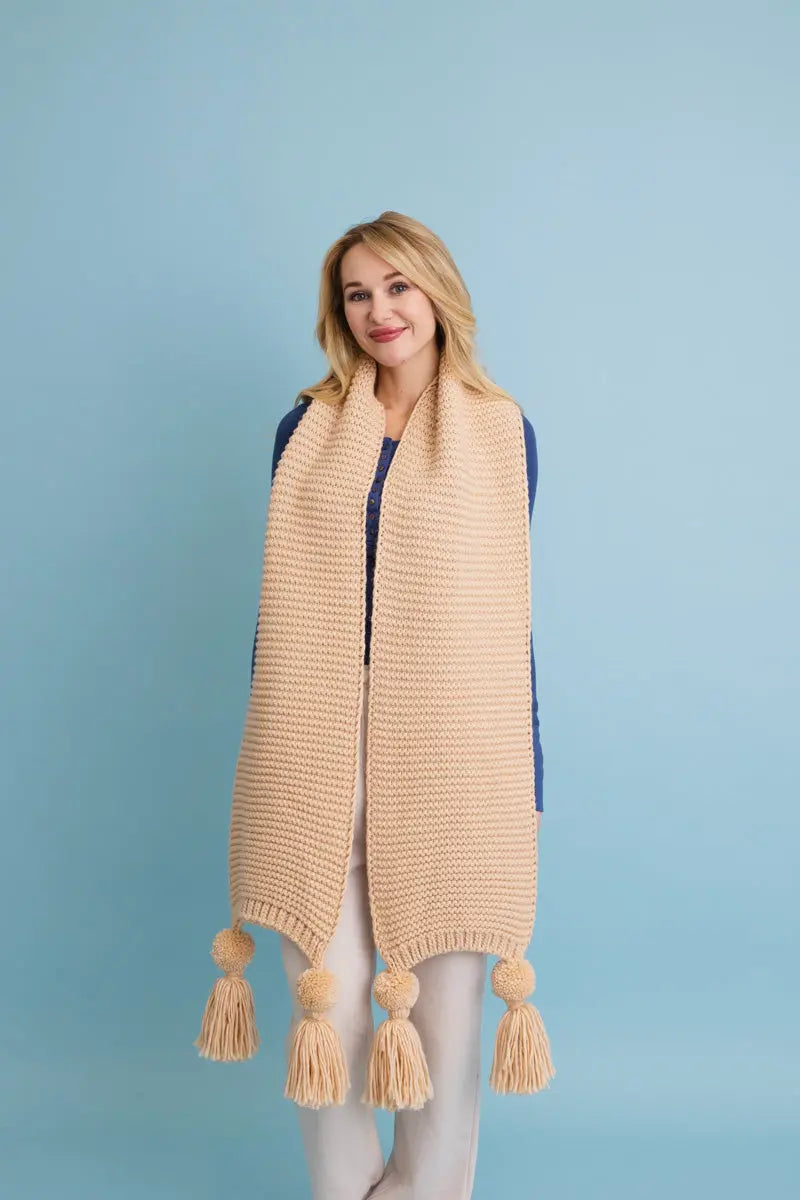 Tan knit scarf with fringed pom-pom ends, draped over shoulders