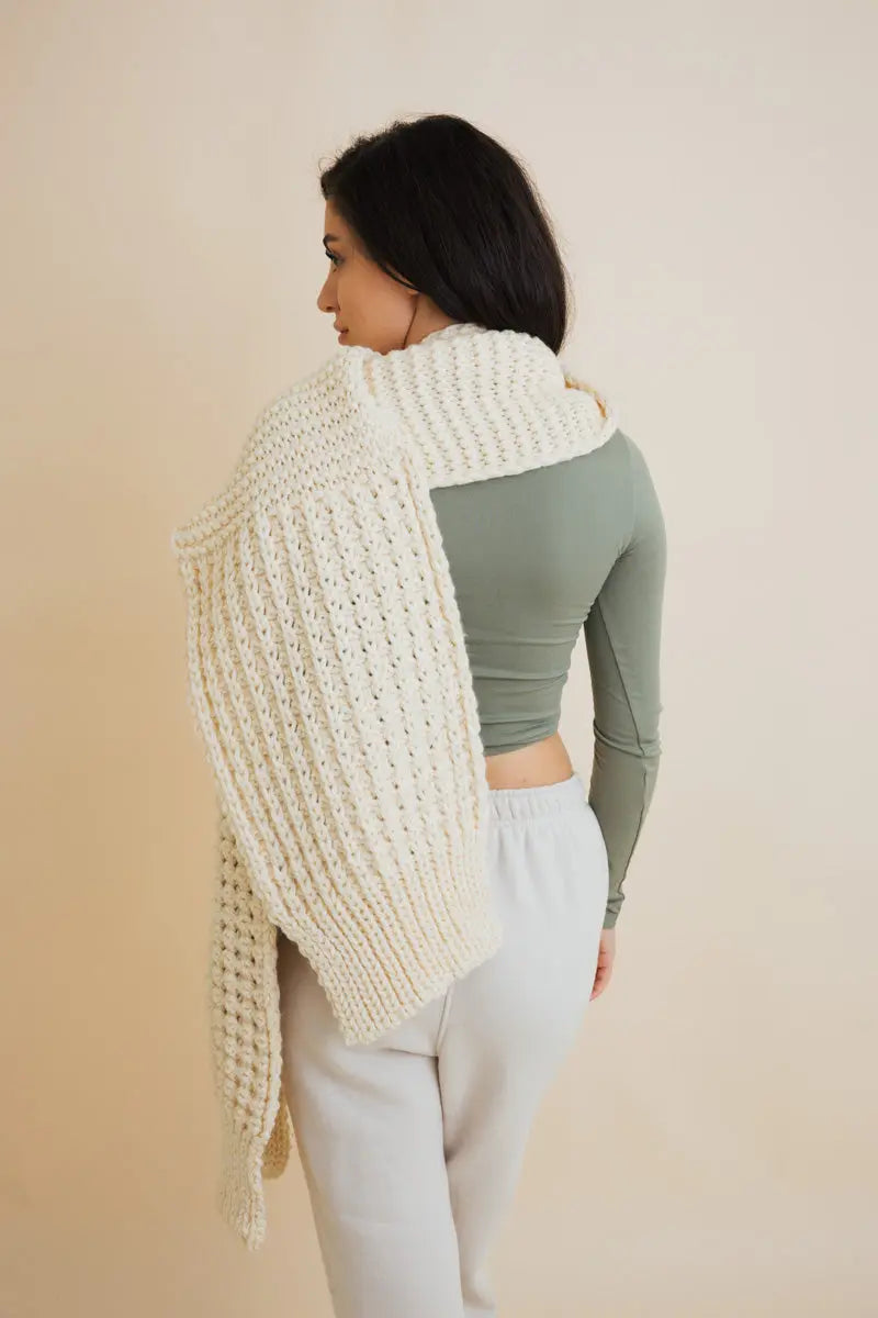 Ivory waffle-knit scarf with fringed ends, worn over shoulders from the back
