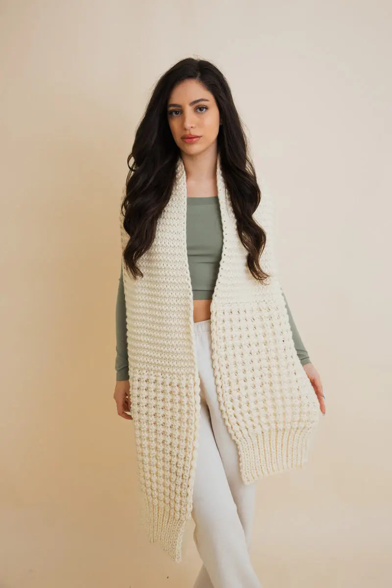 Ivory waffle-knit scarf wrap with fringe trim, worn over the front
