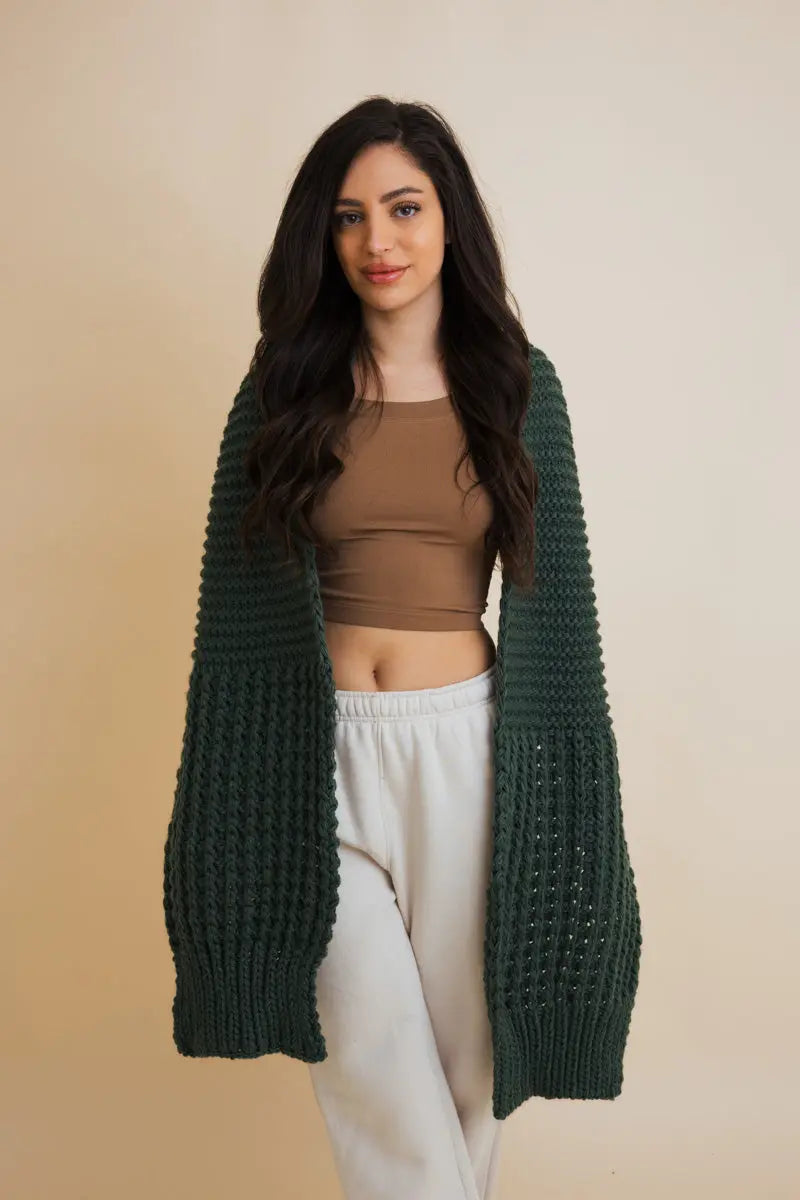 Green waffle-knit scarf with open-knit texture, draped like a wrap over arms