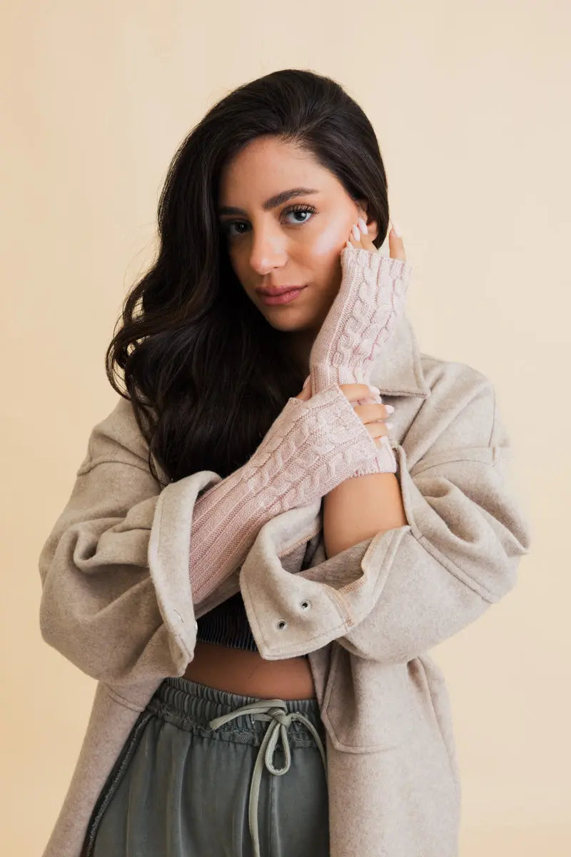 Pink cable-knit fingerless gloves with braided cable pattern and ribbed cuffs