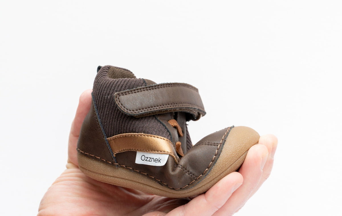 Kids barefoot boot close-up: dark brown upper, tan strap, elastic collar, hook tab