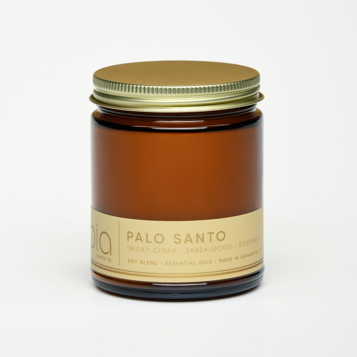 Amber glass soy candle jar with gold lid and “Palo Santo” label, no flame