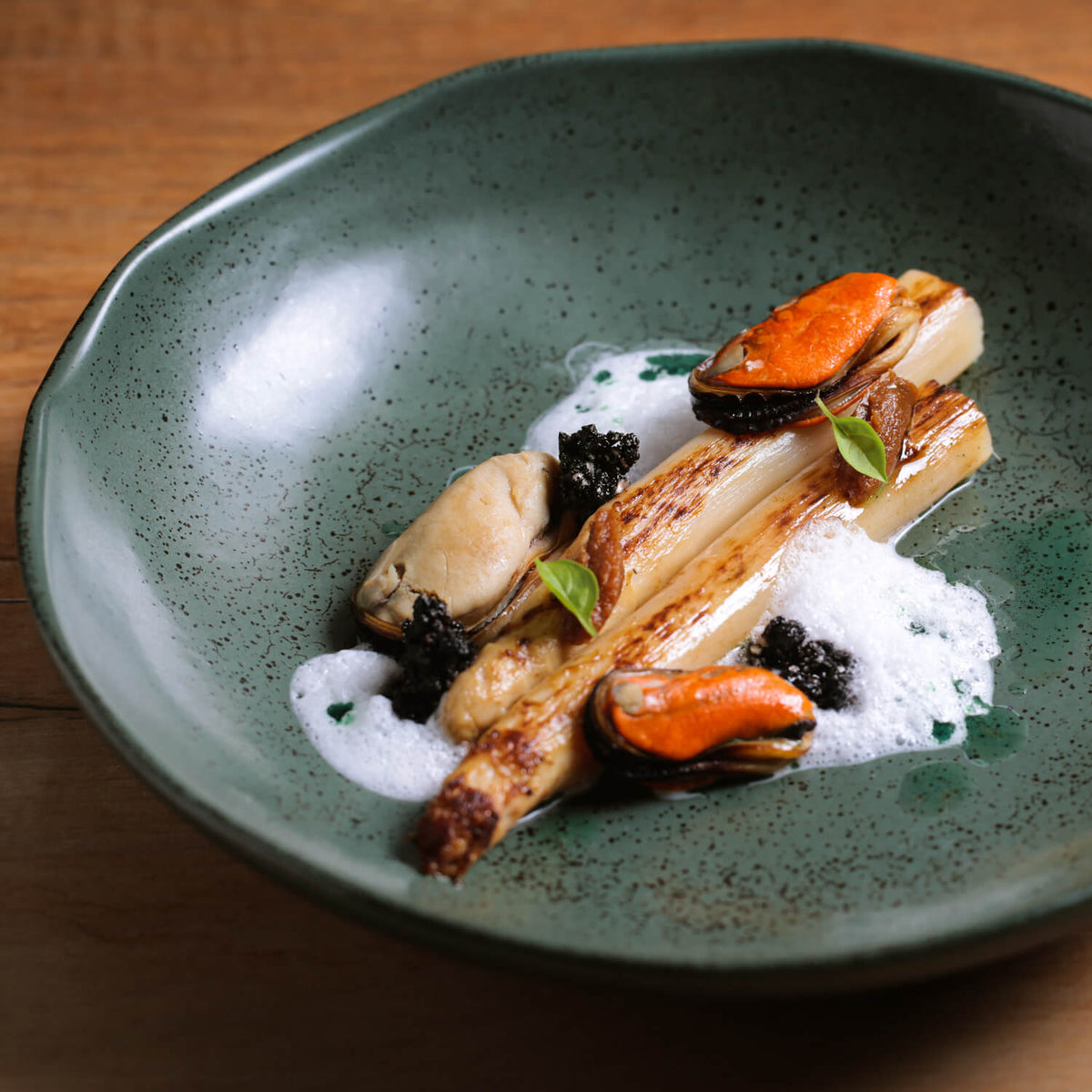 Reactive glazed pasta plate holding prepared meal, dark green speckled surface