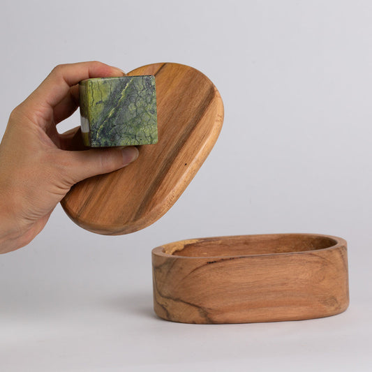Oval wooden jewel box with lid open; green stone knob held in hand